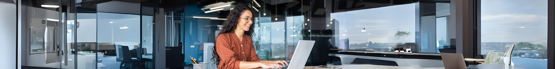 Woman smiling while using a laptop in an office setting